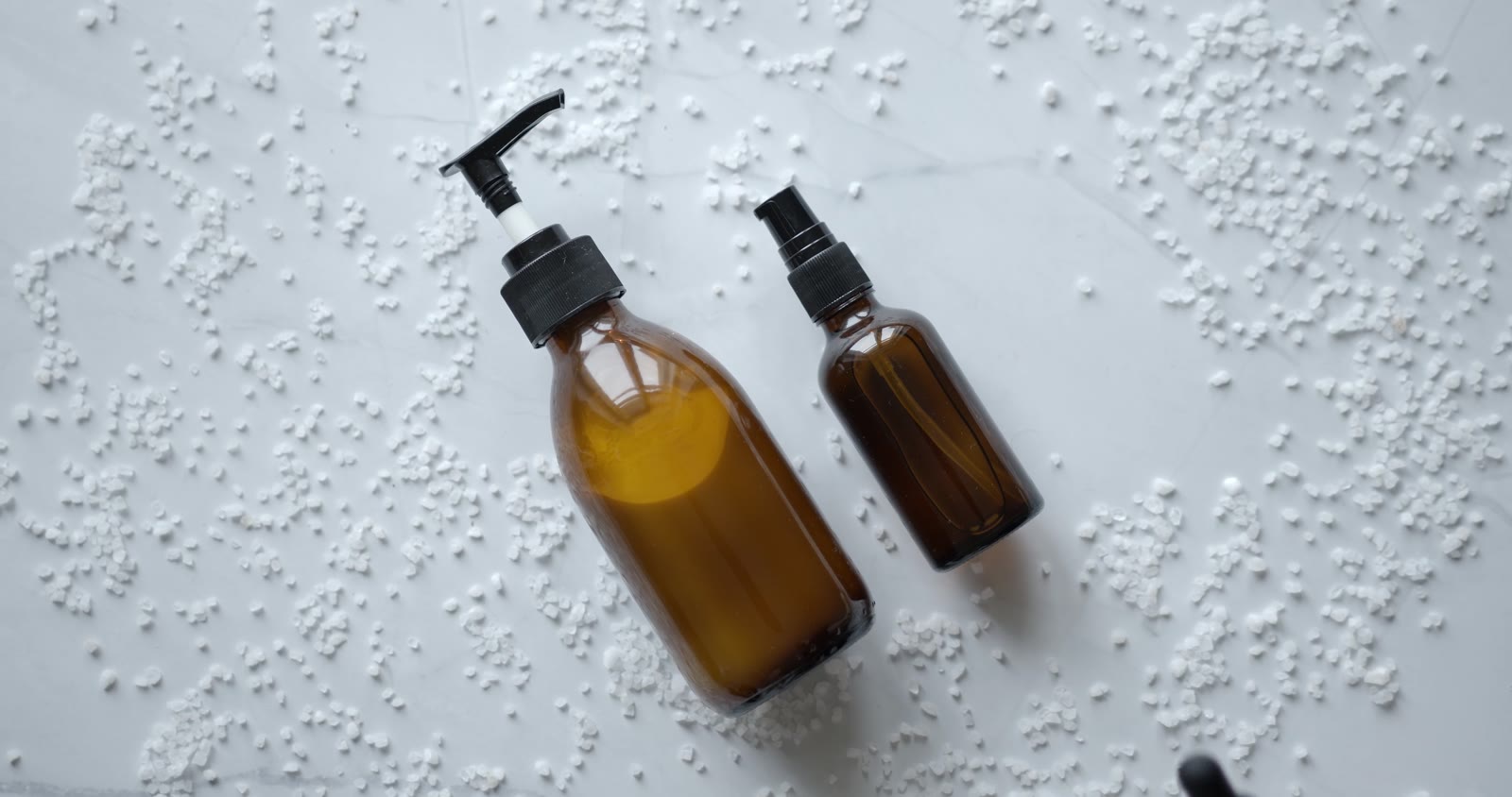 Editorial product display of cosmetic bottles on an ivory surface